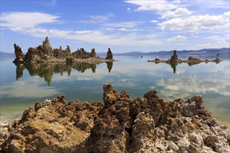 Tranquil lake landscape with unique rock formations and reflections in the water under a blue sky,