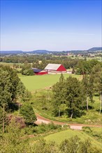 View at a beautiful cultivated landscape with a red barn in the countryside a sunny summer day,
