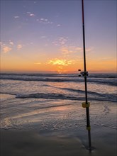 Fishing rod on beach at sunset, surfing cast