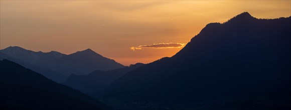Sunset over mountain peaks, clouds in the evening light after sunset, panoramic shot, view from the