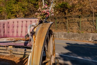 Back seat and left rear wheel of old dilapidated antique horse drawn carriage in South Korea