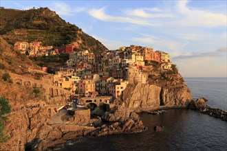 Morning sun shines on a colourful coastal town on the Italian Riviera with a view of the calm sea,
