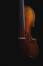 A violin illuminated on a black background that radiates elegance and art