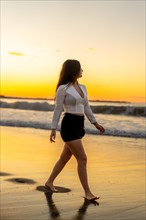 Vertical photo of a sensual woman with skirt and elegant clothes walking along the seaside during