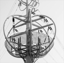 Black and white closeup of large, round, cable transition tower with washed out sky in background