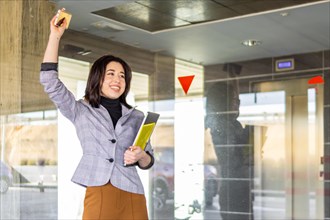 Woman in formal suit saying goodbye to a person outdoors. Portrait of smiling business girl waving