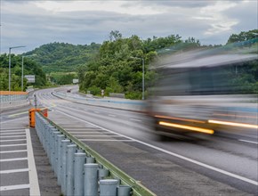 Streaks of light and blur of passing vehicle on highway in countryside location during blue hour