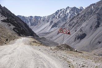 Warning sign at the mountain pass, Dangerous gravel road in the mountains in the Tien Shan,