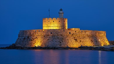 Night view of a castle with a brightly lit lighthouse and soft blue sky, night shot, Fort of Saint
