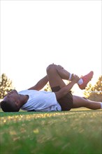 Football player with leg pain on the field. Football player lying on the grass rubbing his leg.