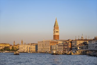 Campanile bell tower and Doge's Palace at sunrise, view from the promenade over the water, Venice,
