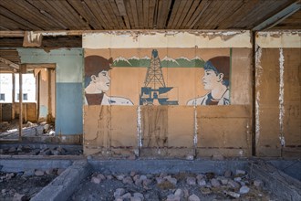 Destroyed abandoned classroom of the old school, wall painting with Soviet miners, ghost town,