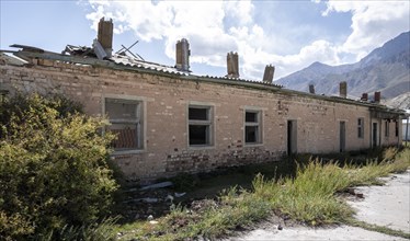 Abandoned buildings in a barren landscape, ghost town of Enilchek in the Tien Shan Mountains,