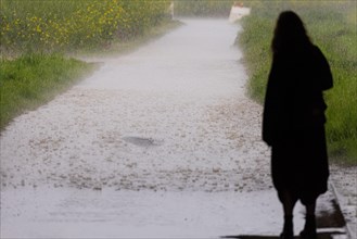 A woman watches as heavy rain floods a country lane in the north-west of Frankfurt am Main,