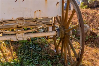 Rear undercarriage and wooden wheel on old rusted horse drawn carriage in South Korea