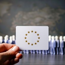 Hand holds a card with EU symbol in front of a row of human figures, AI generated