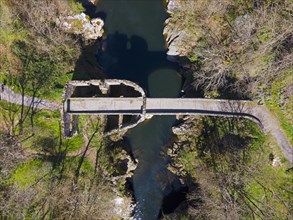 Bird's eye view of an old stone bridge over a quiet river with surrounding vegetation, Bridge of