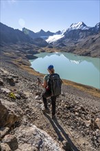 Trekking, hiker in the Tien Shan high mountains, mountain lake Ala-Kul Lake, 4000 metre peak with