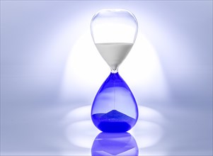 Transparent hourglass with blue sand and blue lighting, creates a shiny reflection effect