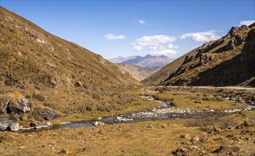 Autumn mountain landscape with yellow grass, mountain stream at Ak-Tog Pass, road to Karkyra
