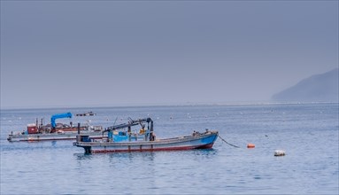 Anchored fishing boat floating in the sea of calm water taken in NamHae, South Korea, Asia