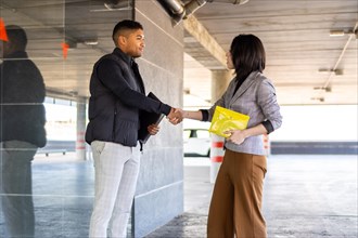 Woman in formal suit shaking hands with casual man outdoors. Business woman shaking hands with guy
