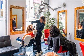 Full length photo of a full beauty salon with hairdresser attending clients