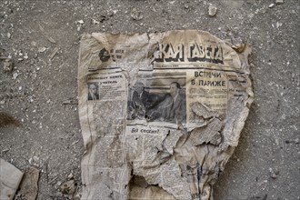 Remains of an old Kyrgyz newspaper from 1924 with Cyrillic writing in an abandoned building, ghost
