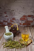Lemon verbena infusion in a glass cup with a marble mortar and pestle and a ceramic teapot with