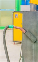 Brown vacuum cleaner handle with hose attached with green duct tape at gas station car wash in