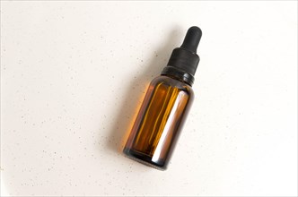 Blank amber glass essential oil (serum) bottle with pipette on cream background. Skin care concept