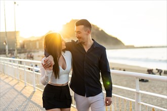 Romantic young couple embracing next to the sea while strolling along a promenade