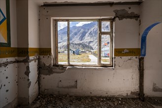 View through a window onto the mountain landscape, abandoned destroyed room with colourful wall