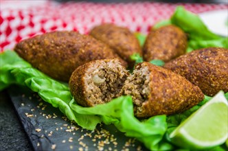 Delicious Lebanese (Arabic) food, kibbeh (kibe) with sauces and lemon on black slate stone and