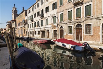 Narrow canal with moored boats and Renaissance architectural style residential palace buildings,