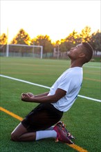 Soccer player on his knees celebrating a goal. Excited footballer man celebrating a goal