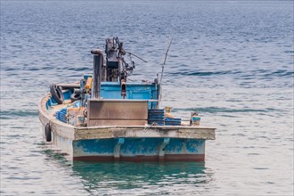 Blue wooden fishing boat floating in a sea of calm water taken in NamHae, South Korea, Asia