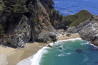 A powerful waterfall flows between rocky cliffs into the sea, Big Sur Pfeiffer, US 1, North
