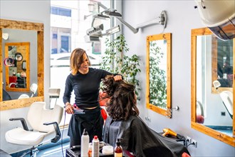 Hairdresser and woman in a beauty salon while they are ironing the hair