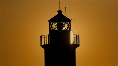 A lighthouse in silhouette with a dazzling sunrise in the background, sunrise, dawn, Fort of Saint