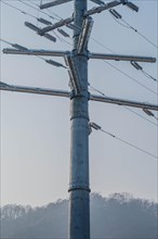 Closeup of large futuristic looking cable transition electrical tower with hazy blue sky background