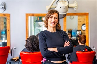 Portrait of a happy and proud hairdresser standing with arms crossed and smiling at camera in the
