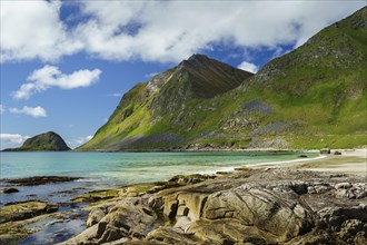 Landscape with sea at the sandy beach of Haukland (Hauklandstranda) with the mountain Veggen. Rocks