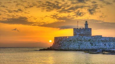 A lighthouse on a fortress wall by the sea during a colourful sunrise, sunrise, dawn, lighthouse,