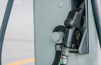 Closeup of gas pump handle with black rubberized cover inserted into side of gas pump in South