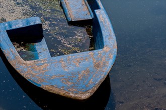 Closeup of blue fishing boat filled with dirty water floating in river in South Korea