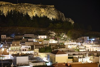 Lindos village, night view of a town with illuminated buildings and a fortress on a hill, Lindos,