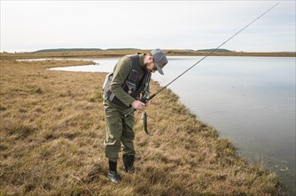 Sport fisherman fishing in lake on cloudy day, Cambara do sul, Rio Grande do sul, Brazil, South