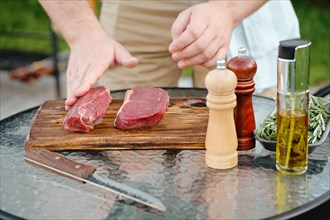 Unrecognizable man rubbing olive oil with hand over raw beef strip steak