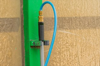 Closeup of handle of car wash brush with attached blue water hose in South Korea